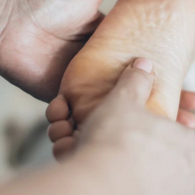 A very zoomed in shot of hands performing reflexology on a bare foot.